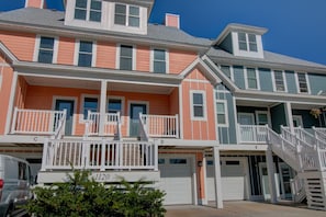 A multi-story residential building with a two-story balcony on the ground floor, a garage, and a staircase leading to the upper floor.