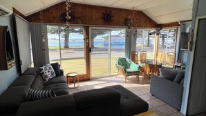A cozy living area with a sofa, a dining table, and a view of the outdoors. - Family Friendly Shack with Bay Views (Fisherman bay)