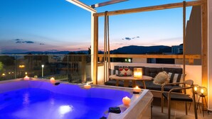 Eine Dachterrasse mit Whirlpool, Sitzgelegenheit und Kerzen.
