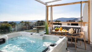 Eine Dachterrasse mit Whirlpool, Sitzgelegenheit und einem Tisch mit Getränken.