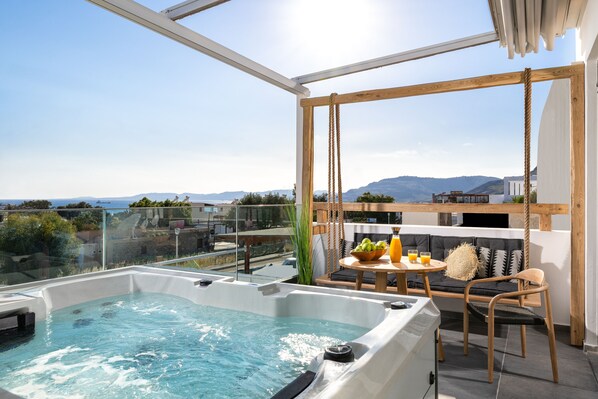 A rooftop terrace with a hot tub, seating area, and a table with drinks.