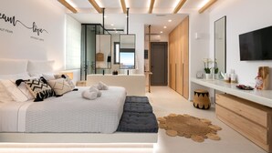 Ein modernes Schlafzimmer mit einem großen Bett, Nachttischen, einem Fernseher und einem Spiegel.