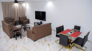 A modern living room with a sofa, chairs, a coffee table, and a dining area with a table and chairs. - Gated Community (Lashibi, Tema)