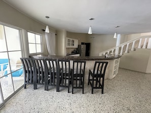 A spacious kitchen with a central island, bar stools, and a staircase leading to an upper level.