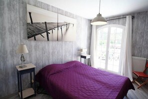 A bedroom with a bed, a nightstand, a lamp, a window with curtains, and a view of the outside. - Perfect villa with pool - fantastic location A3693 (Lège-Cap-Ferret)