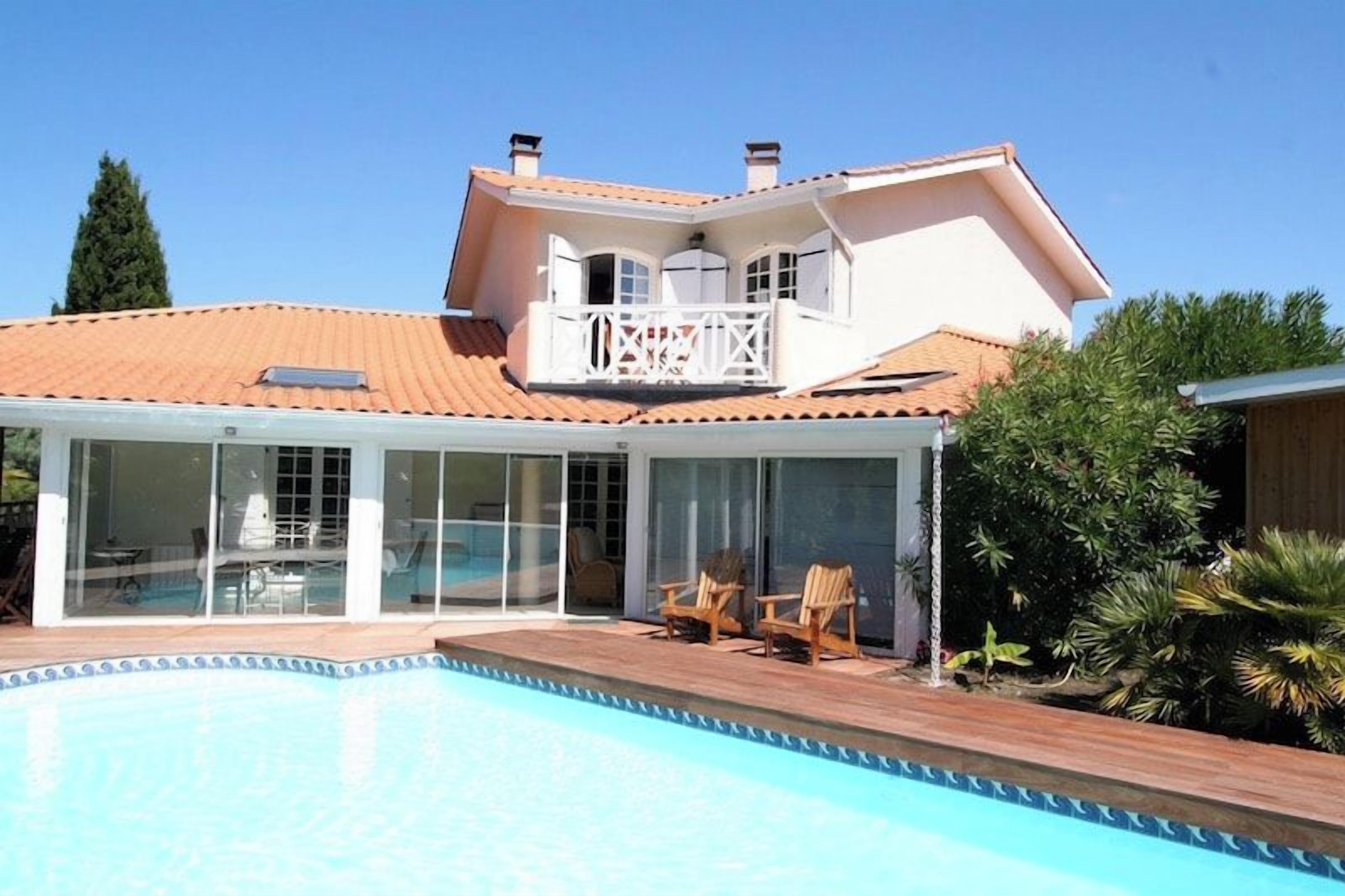 Ein Haus mit Schwimmbad, einer überdachten Terrasse und einem Balkon.