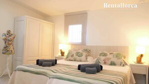 A bedroom with a bed, nightstands, a wardrobe, and a window. - Es Collet by Rentallorca (Manacor)
