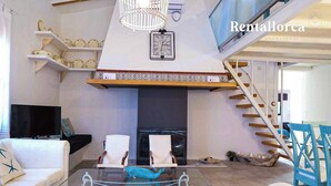 A modern living room with a fireplace, white sofas, a glass coffee table, and a staircase. - Es Collet by Rentallorca (Manacor)