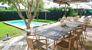 An outdoor dining area with a table and chairs, a pool, and a pergola with hanging lights. - Es Collet by Rentallorca (Manacor)