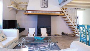 A modern living room with a fireplace, white sofas, a glass coffee table, and a staircase. - Es Collet by Rentallorca (Manacor)