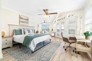 Une chambre Ă coucher comprenant un lit, un bureau, une chaise, un ventilateur de plafond et une fenĂȘtre avec des stores.