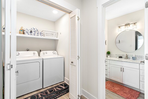 A laundry room with two white washing machines, a drying rack, and a door mat with the word 'DRY'.