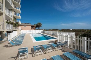 Relax by the pool surrounded by lounge chairs and palm trees.