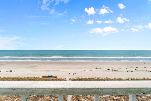 Guests can enjoy a peaceful beach experience with umbrellas providing shade and a grassy area nearby.
