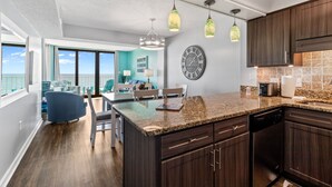 A modern kitchen with dark wood cabinets, a granite countertop, and pendant lighting. - Crescent Sands In Windy Hill D6 3 Bedroom Condo by RedAwning (North Myrtle Beach)