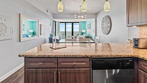 A kitchen with granite countertops, dark wood cabinets, a dishwasher, and a clock on the wall. - Crescent Sands In Windy Hill D6 3 Bedroom Condo by RedAwning (North Myrtle Beach)