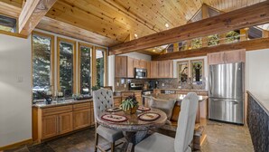 A spacious kitchen with wooden cabinets, a stainless steel refrigerator, and a dining area with a round table and chairs. - Lake View 2BR/2BA Incline Village w/ Fireplace (Incline Village)