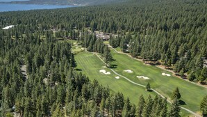 A golf course surrounded by dense forest with a lake in the background. - Lake View 2BR/2BA Incline Village w/ Fireplace (Incline Village)
