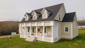 Ein zweistöckiges Haus mit umlaufender Veranda, Eingang und Garage.