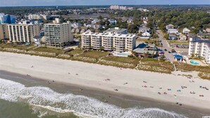 Zona hotelera costera con varios edificios altos, una playa de arena y vistas al océano.
