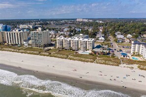 Zona hotelera costera con varios edificios altos, una playa de arena y vistas al océano.