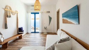 A modern living room with a wooden bench, a white sofa, and a hanging light fixture.