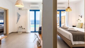 Et moderne hotelværelse med seng, natbord og udsigt til stranden gennem vinduet.