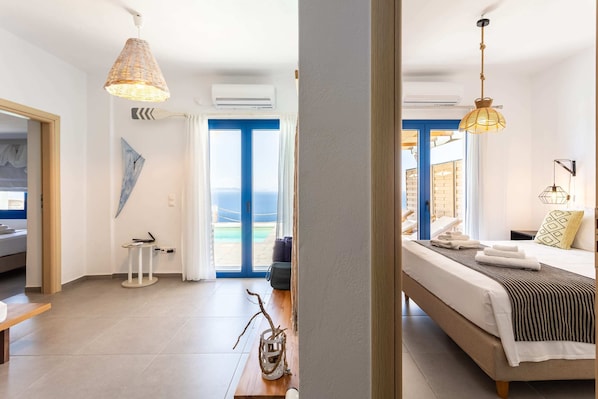 Une chambre d’hôtel moderne, équipée d’un lit, d’une table de chevet et offrant une vue sur la plage par la fenêtre.