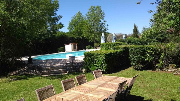 A backyard with a pool, a wooden table, and chairs. - Tulip Gîte in a Quercy stone house (Saint-Antonin-Noble-Val)