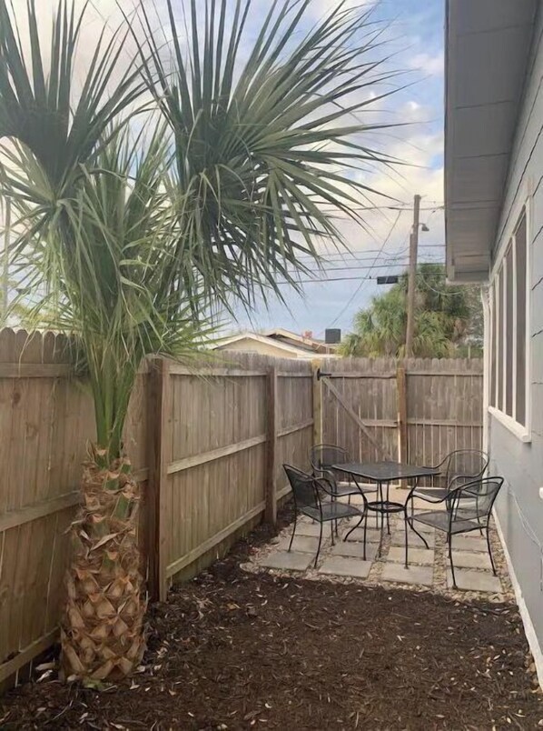 Enjoy outdoor dining or relaxation in this patio area with a palm tree and seating for four.