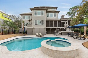 A two-story house with a swimming pool and hot tub.