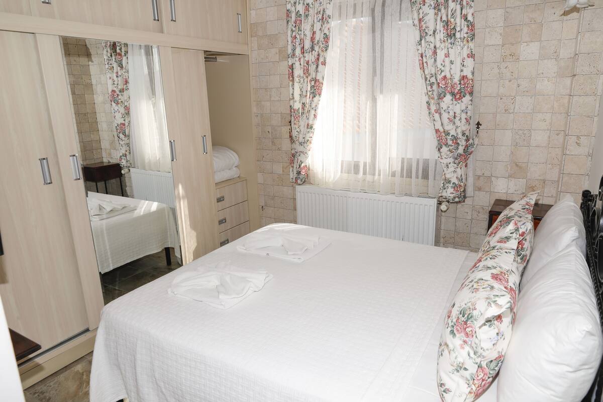A bedroom with a bed, a wardrobe, and a window with curtains.