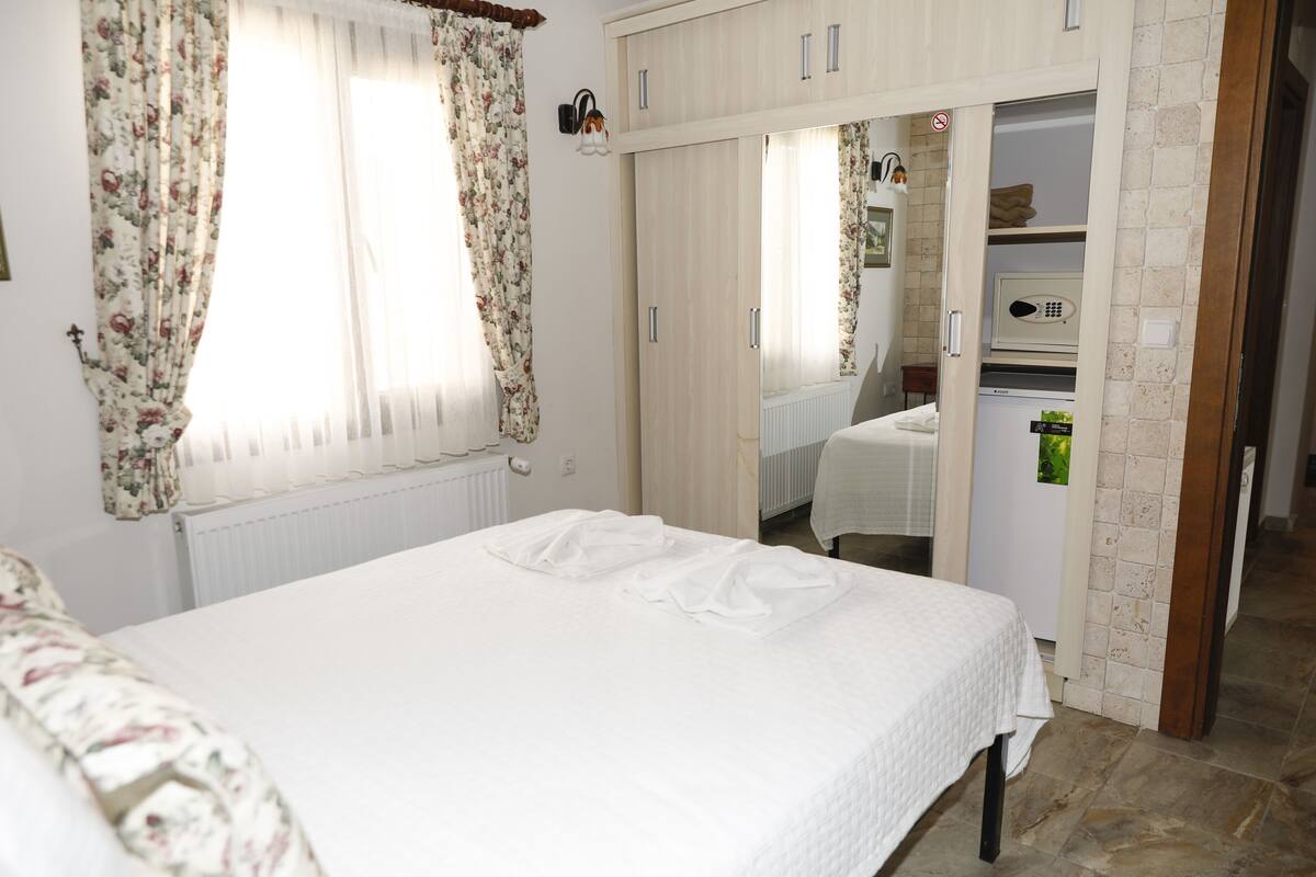 A bedroom with a bed, a wardrobe, and a bathroom visible through an open door.