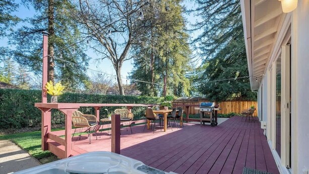 Une terrasse dotée d’un jacuzzi, de mobilier d’extérieur et d’une clôture en bois.