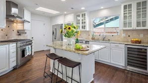 A modern kitchen with white cabinetry, a granite countertop, and stainless steel appliances.