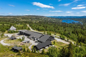 A large building complex surrounded by forested areas and a lake.
