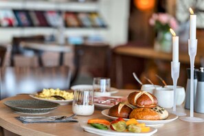 A breakfast setting with various dishes, including bread, fruits, and a candle.