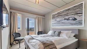 A neatly arranged bedroom with a bed, a chair, a TV, and a large abstract painting on the wall. - Ranten Hotell, BW Signature Collection (Nes)