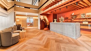A spacious lobby with a high ceiling, wooden flooring, a reception desk, and a dinosaur statue. - Ranten Hotell, BW Signature Collection (Nes)