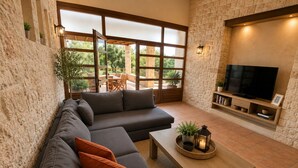 Un soggiorno moderno con un divano componibile, un tavolino in legno e una TV su una parete in pietra.