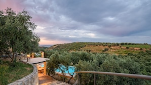 Una scala in pietra conduce a una zona piscina con vista su un paesaggio rigoglioso e colline lontane.