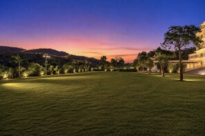 A well-lit grassy area with trees and a building in the background. - Mewar Palace Luxury Resort & Private Pool Villas - Udaipur (Udaipur)