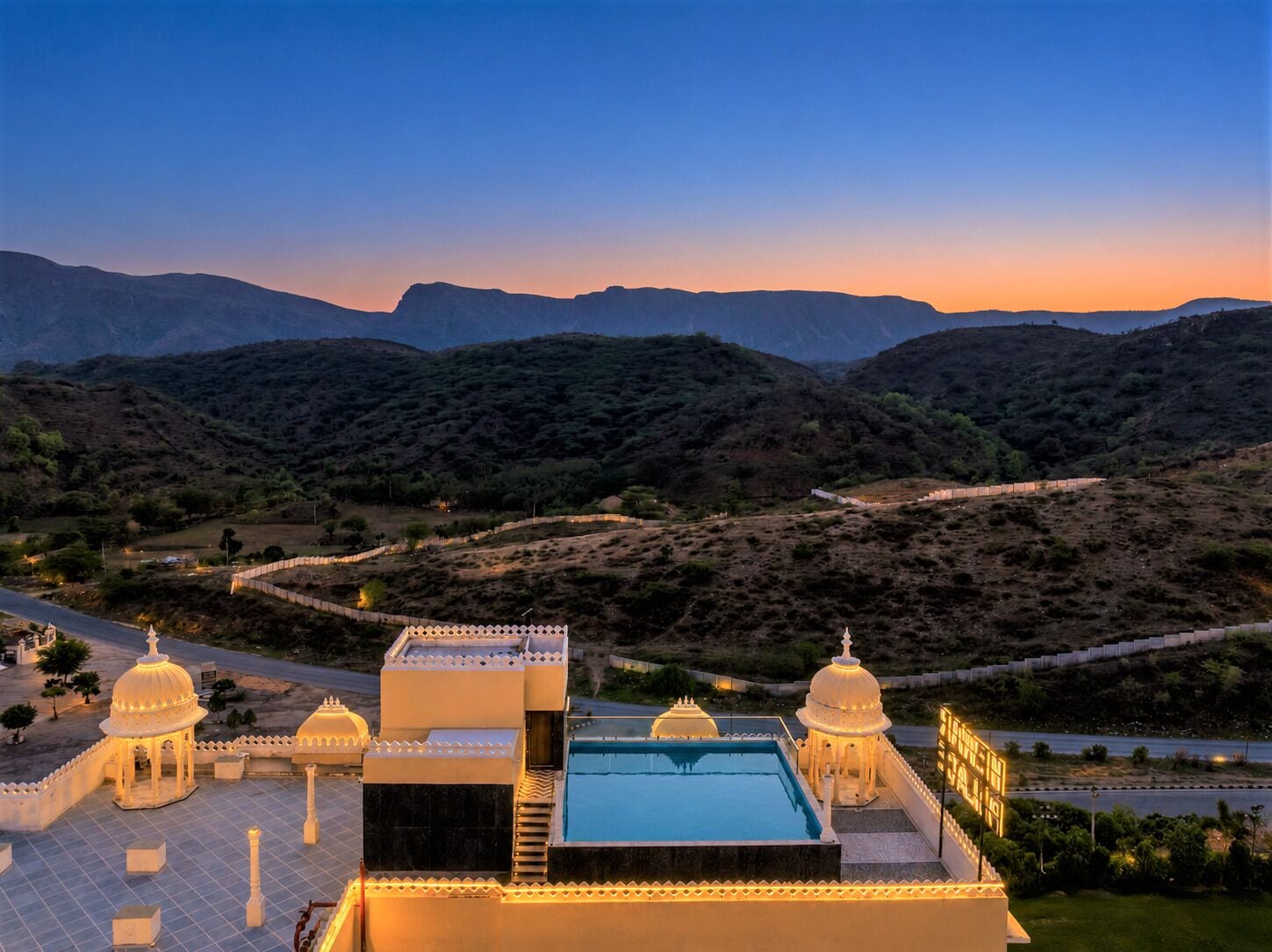A resort with a swimming pool, multiple domed structures, and a view of a valley with mountains in the background.