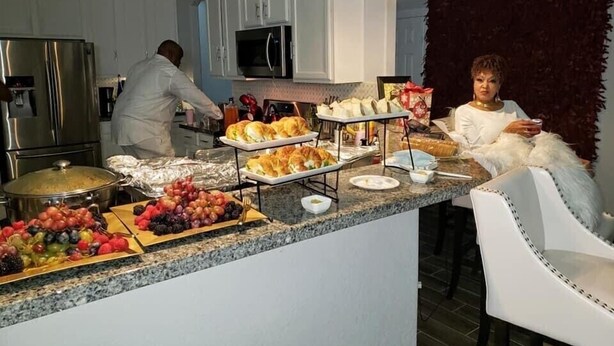 Eine Küche mit einem Buffet, das verschiedene Speisen und eine Person beim Zubereiten von Essen zeigt.