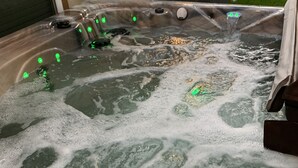 Ein Whirlpool mit zahlreichen Düsen, einer Steuerung und einer Holzterrasse.