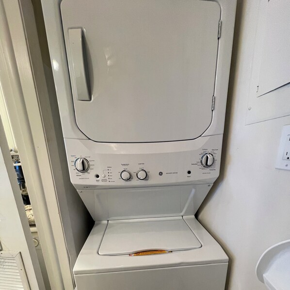 A front view of a white washing machine with control knobs and a front-loading door.