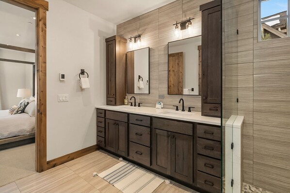 Un baño moderno con tocador doble, muebles de madera y un espejo grande.