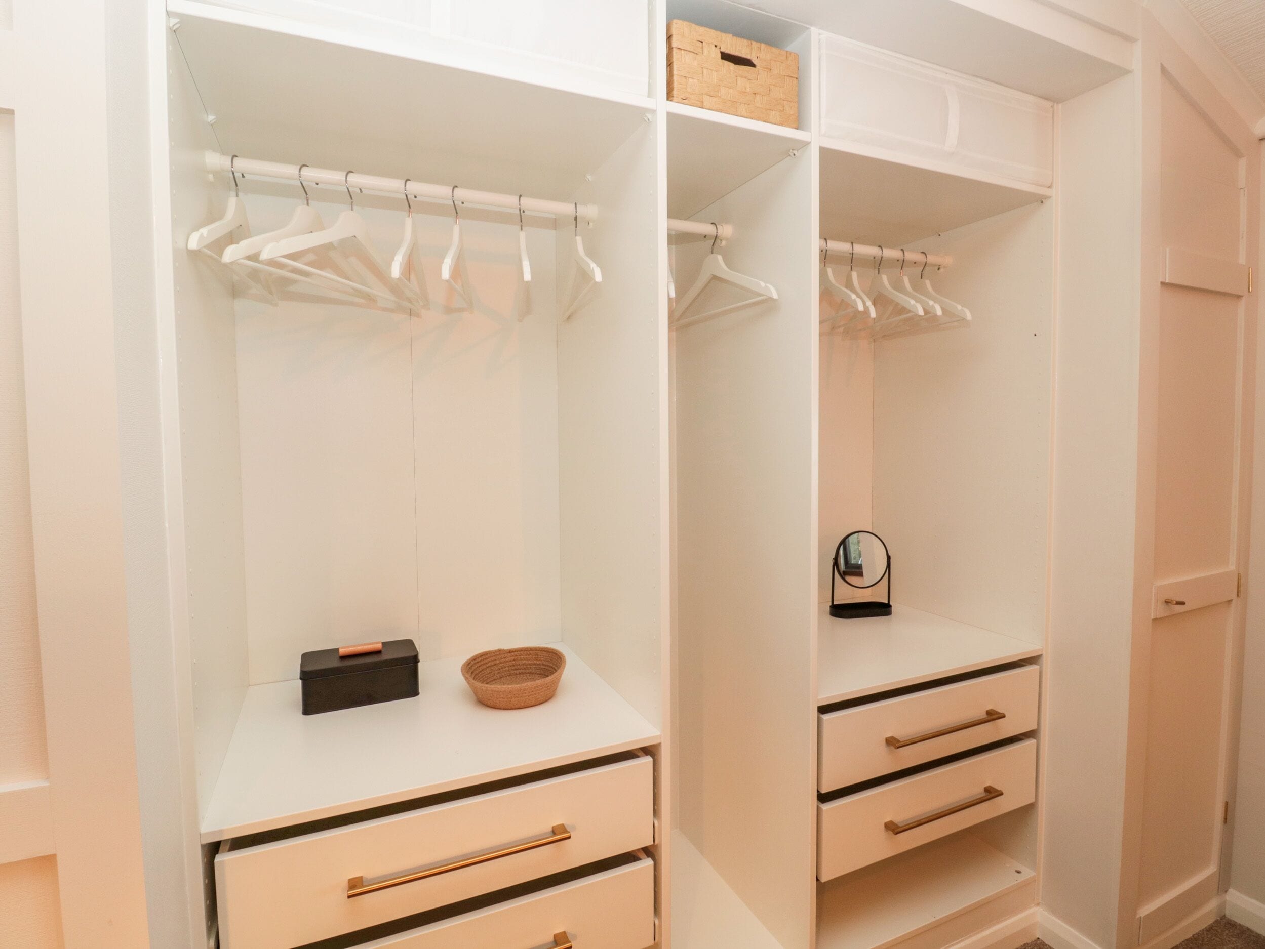 A white walk-in closet with open shelves, hanging space, and drawers.