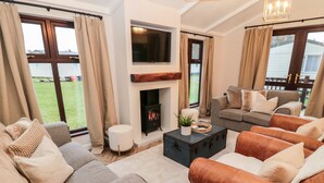 A living room with a fireplace, sofas, and a television. - The Treeline (Morpeth)