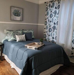 Quarto com cama, almofadas, bandeja e planta em vaso.